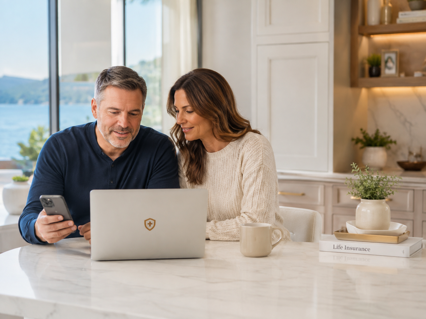 Couple reviewing life insurance options together in a bright kitchen with a laptop and phone